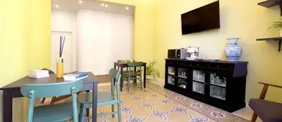 a living room with a table and chairs and a tv at Antista Rooms in Palermo
