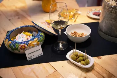 a table with a plate of food and a glass of wine at Casavacanze Tuttapposto in Palermo