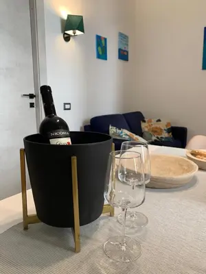 a bottle of wine in a black bucket on a table with two glasses at Kemonia Home Palermo in Palermo