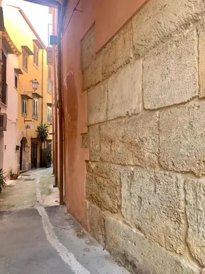 an alley with a stone wall next to a building at Kemonia Home Palermo in Palermo
