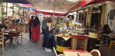 a group of people in a market with people sitting at tables at Loft Mercede al Capo in Palermo