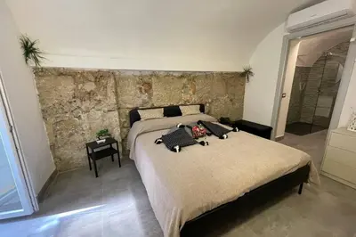 a bedroom with a large bed and a stone wall at Tufoletto Apartment in Palermo