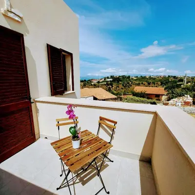 a wooden bench on a balcony with a potted plant at Terrazza del Golfo in Castellammare del Golfo