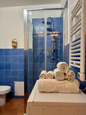 a blue tiled bathroom with a pile of towels at Piazza Marina Apartment in Palermo