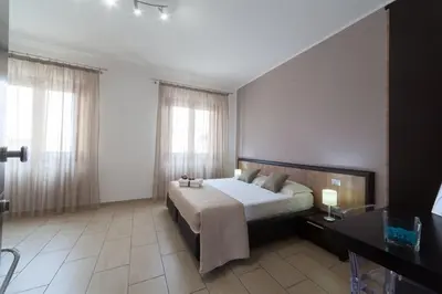 a bedroom with a bed and a desk and windows at Kristal in San Vito lo Capo