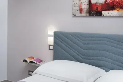 a bedroom with a bed and a painting on the wall at Alofara Apartment in San Vito lo Capo