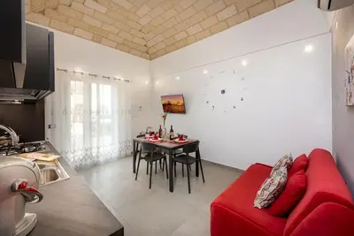 a living room with a red couch and a table at Alofara Apartment in San Vito lo Capo