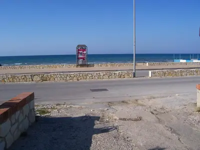 an empty road next to the beach with a gas station at La Perla del Golfo in Castellammare del Golfo