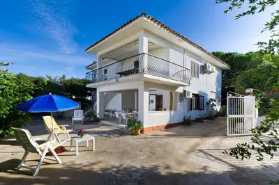 a house with a balcony and two chairs and an umbrella at La Perla del Golfo in Castellammare del Golfo