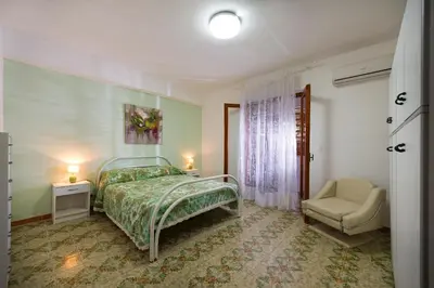 a bedroom with a bed and a chair at La Perla del Golfo in Castellammare del Golfo