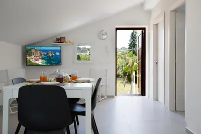 a white dining room with a white table and chairs at Appartamenti in Villa Nature con vista mare e monti in Scopello