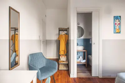 a living room with a blue chair and a mirror at Dante Suites in Palermo