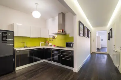 a kitchen with black and white cabinets and yellow walls at Celestre all'Alloro by DomuSicily in Palermo