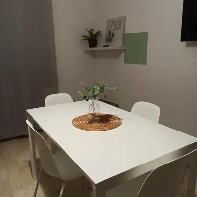 a white table with chairs and a vase of flowers on it at Casa Melf in Terrasini