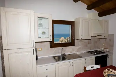 a kitchen with white cabinets and a sink and a window at Sicilia Ovest - Sea View Terrace Sofia in Castellammare del Golfo
