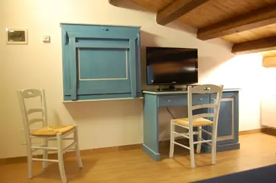 a blue desk with a tv and two chairs at Sicilia Ovest - Sea View Terrace Sofia in Castellammare del Golfo