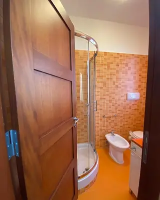 a bathroom with a shower and a toilet and a door at L'Oasi dell'Eremita in Mondello