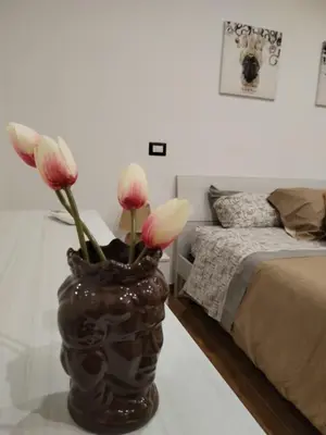 a vase with pink and white flowers in a bedroom at Momaliar House in Campofelice di Roccella