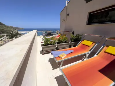 a balcony with chairs and tables on a building at Sicilia Ovest - Terrazza Orologio e Terrazza Sul Mare in Castellammare del Golfo
