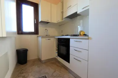 a kitchen with white cabinets and a black stove at Sicilia Ovest - Balcone Bellavista in Castellammare del Golfo