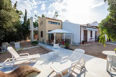 a patio with chairs and a table and a house at Kòre rooms in Castellammare del Golfo