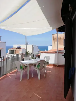 a white table and chairs on a balcony with the ocean at By the Sea Apartment #4 in Terrasini