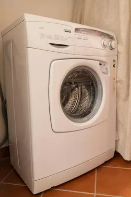 a white washing machine sitting on a tile floor at La Palma in San Vito lo Capo