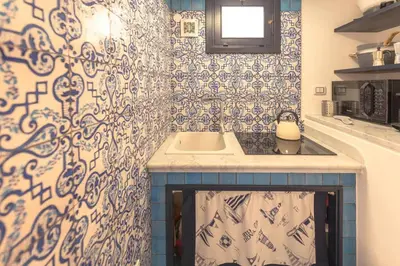 a kitchen with a sink and blue and white tiles at Design loft Marinella in Porticello in Santa Flavia