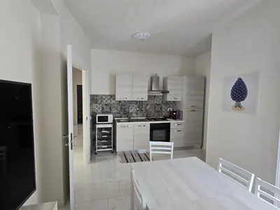 a kitchen with white cabinets and a table in it at casa francesca 2 LOFTY in Castellammare del Golfo
