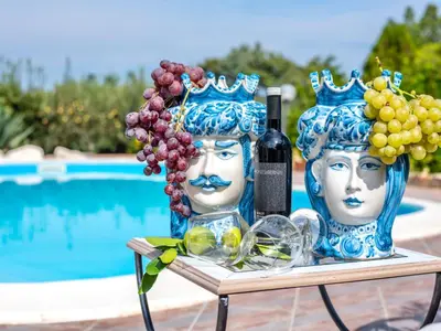 a table with two vases with grapes and a bottle of wine at Villa La Vela by Interhome in Scopello
