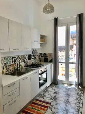a kitchen with white cabinets and a tile floor at Casa Colore Loft in Castellammare del Golfo