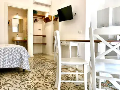a room with a bed and a desk with two white chairs at Casa Colore Loft in Castellammare del Golfo