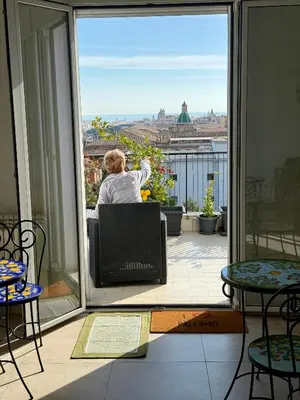 a woman sitting on a chair on a balcony looking out at the city at B&B Bellavista in Palermo