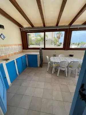 a kitchen with a table and chairs in a room at NEREA - Appartamento fronte mare in San Vito lo Capo