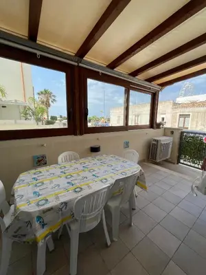 a white table and chairs in a room with windows at NEREA - Appartamento fronte mare in San Vito lo Capo