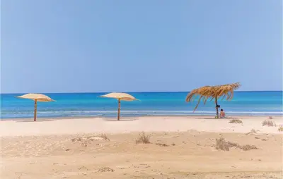 three straw umbrellas on a beach with the ocean at Cozy Apartment In Balestrate With Wifi in Balestrate
