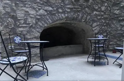 two tables and chairs in front of a stone tunnel at Patio1861 - A Sicilian deluxe apartment in Termini Imerese
