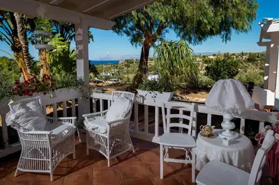 a porch with white chairs and a table with a view at NUOVA Villa Intera Guidaloca in Scopello