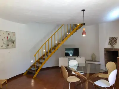 a dining room with a table and a staircase at TORRE MARIZA Guidaloca in Scopello