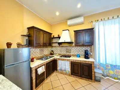 a kitchen with wooden cabinets and a stainless steel refrigerator at Le Maioliche in Sferracavallo