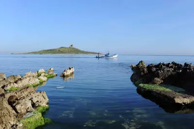 a boat in the water next to an island at Isola bella in Isola delle Femmine