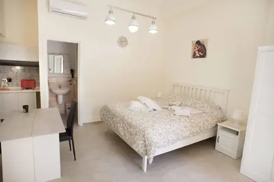 a bedroom with a bed and a desk and a kitchen at Isola bella in Isola delle Femmine