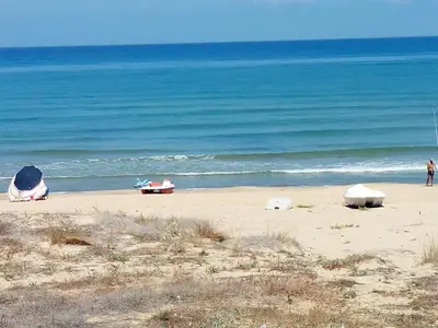 a beach with people on the sand and the ocean at Residenza sabbia dorata in Alcamo