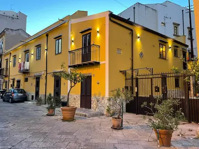 a yellow building on a street with potted plants at Case vacanze donna Ina in Palermo
