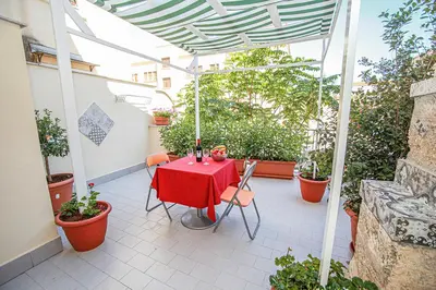 a red table and chairs on a patio with plants at Appartamento con terrazza al centro storico. in Palermo