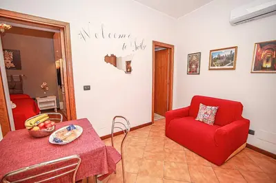 a living room with a red chair and a table at Appartamento con terrazza al centro storico. in Palermo