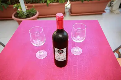 a bottle of wine sitting on a pink table with glasses at Appartamento con terrazza al centro storico. in Palermo