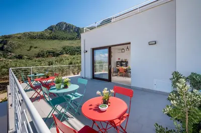 a patio with tables and chairs on a balcony at Villa Maria con piscina e vista mare in Castellammare del Golfo