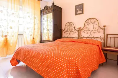 a bedroom with a bed with an orange comforter at Independent Villa Located a few Minutes Walk From the Beach in Quiet Area in Palermo