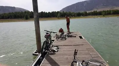 a man standing on a dock on a lake at Flyhouse PARCHEGGIO AUTO BICI GRATUITO in Piana degli Albanesi